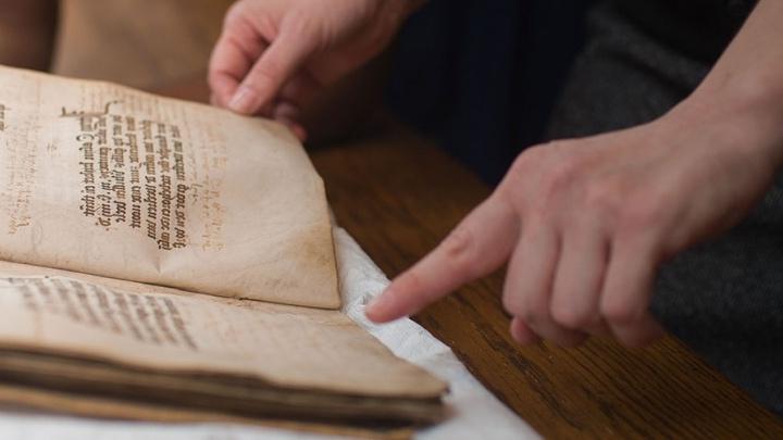Student handles age-worn book in the Coates 图书馆 Special Collections and Archives.