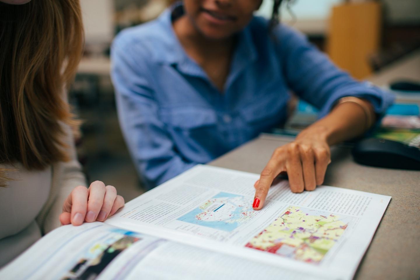 学生指着杂志上的地图 